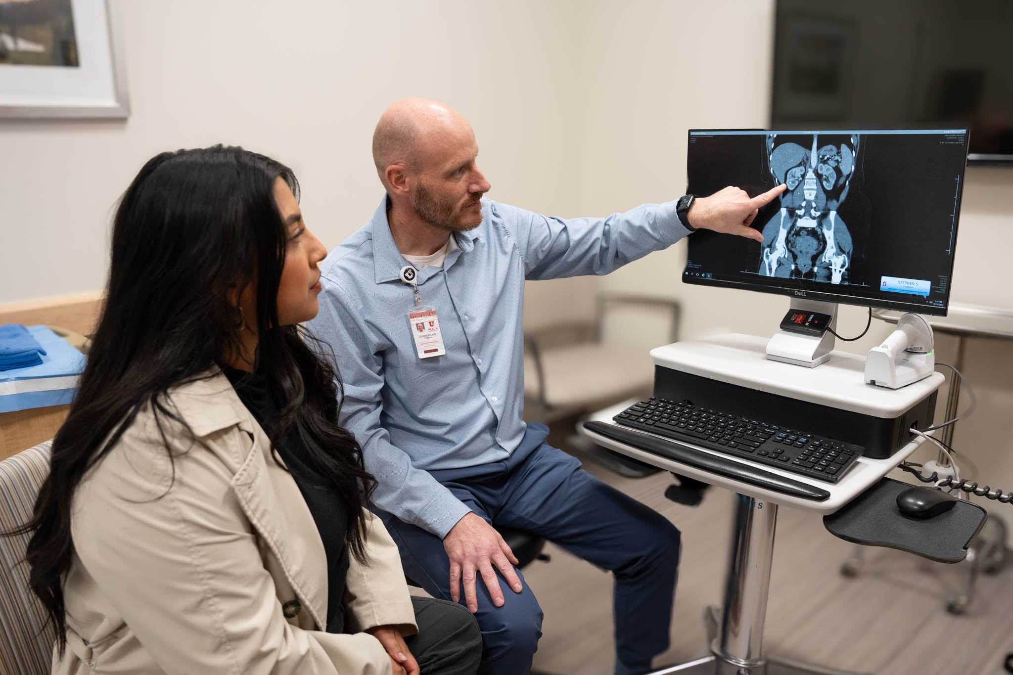 Male urologist points to a kidney scan next to his female patient.