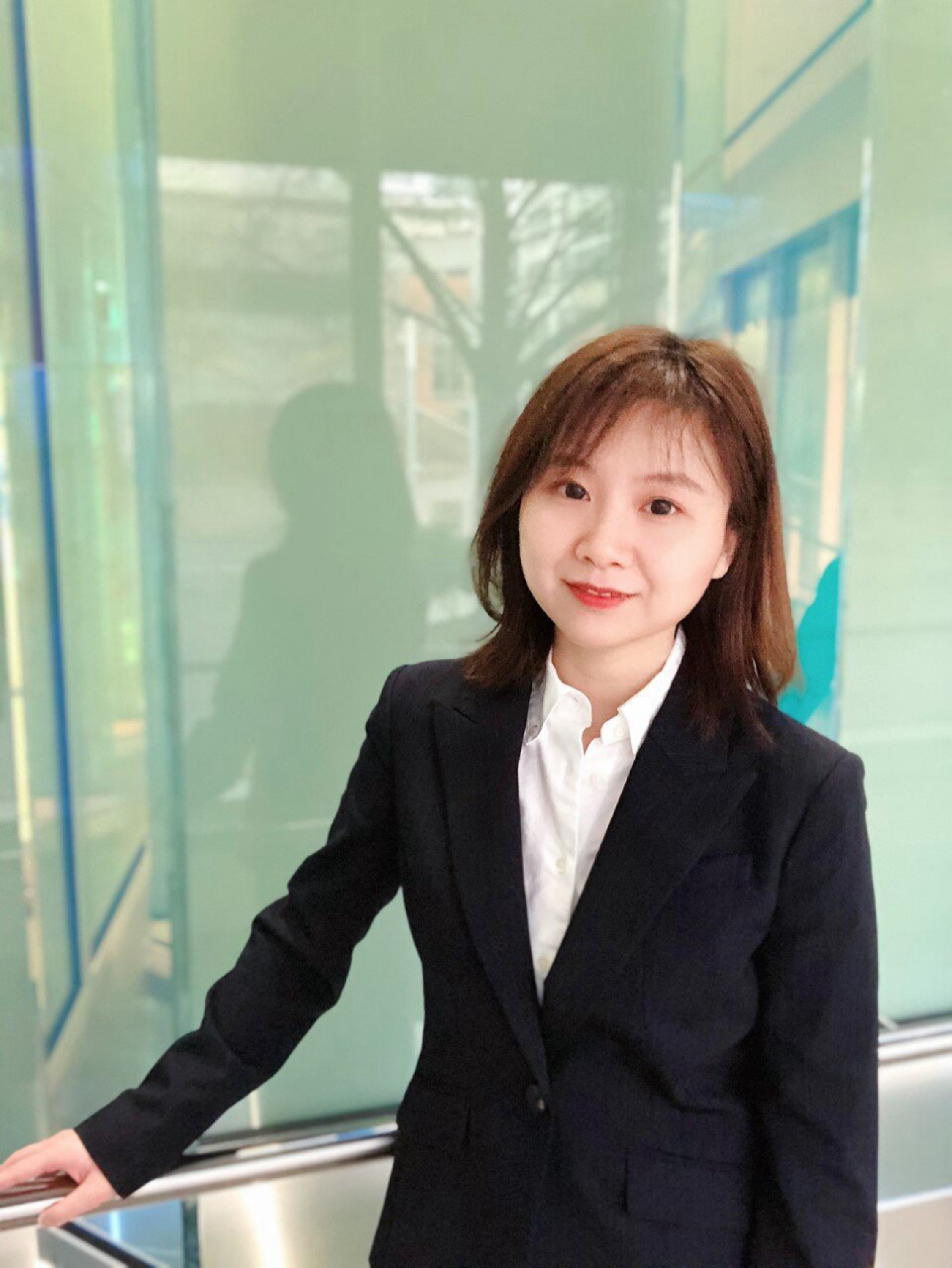 Person in a suit standing beside a window.