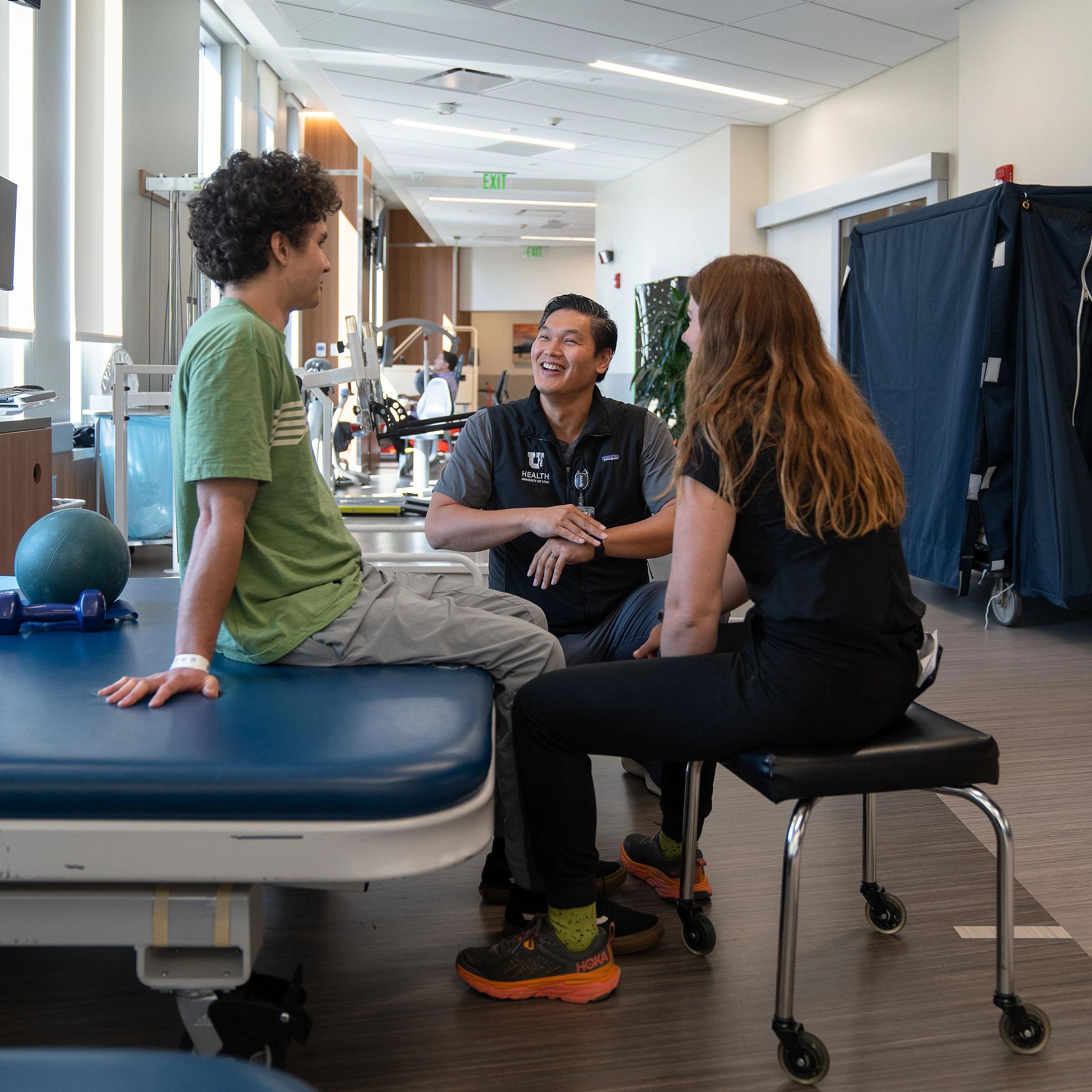 Dr. Park and a Neilsen Rehabilitation Hospital care team member talk with a young patient during a physical therapy session.