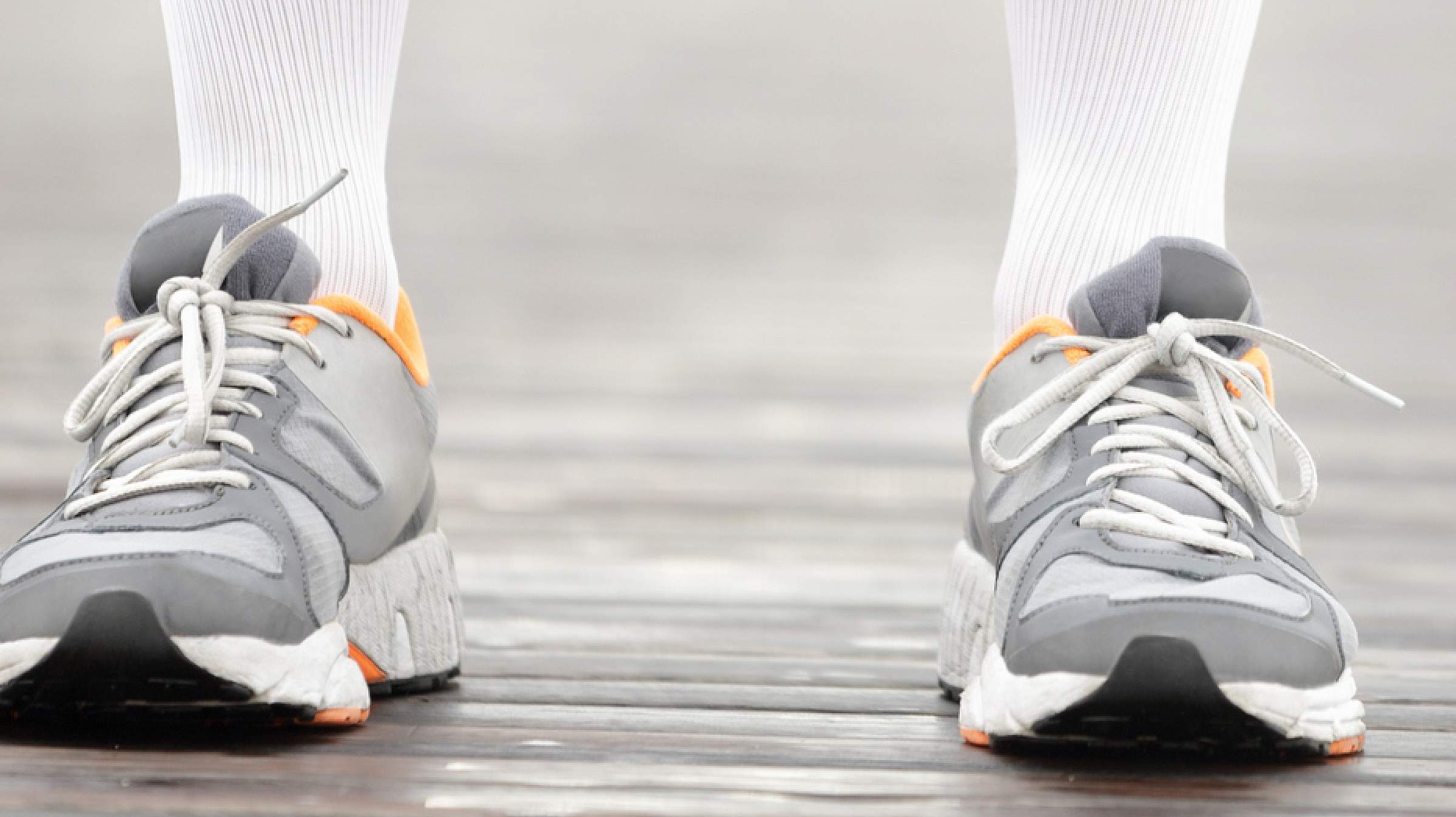 Legs wearing tennis shoes and knee high white compression socks